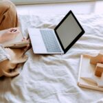 Adult woman working on a laptop while taking notes, showcasing a comfortable home office setting.