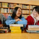 Three diverse students laughing and studying together in a cozy library setting.